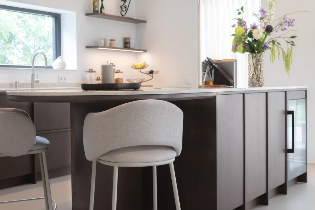 Moderne Japandi-keuken in Friesland met Yuki Ash-kasten, een lichtgrijze barkruk en een vaas met bloemen op het aanrecht.